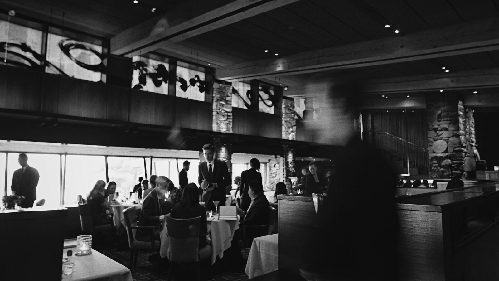 Sprawling view of the Canlis dining room with servers speaking to guests as they dine